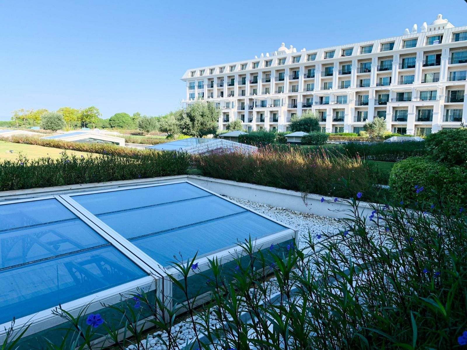 Gartenansicht des Titanic Deluxe Hotels mit gepflegten Grünflächen und einem modernen Gebäudekomplex.