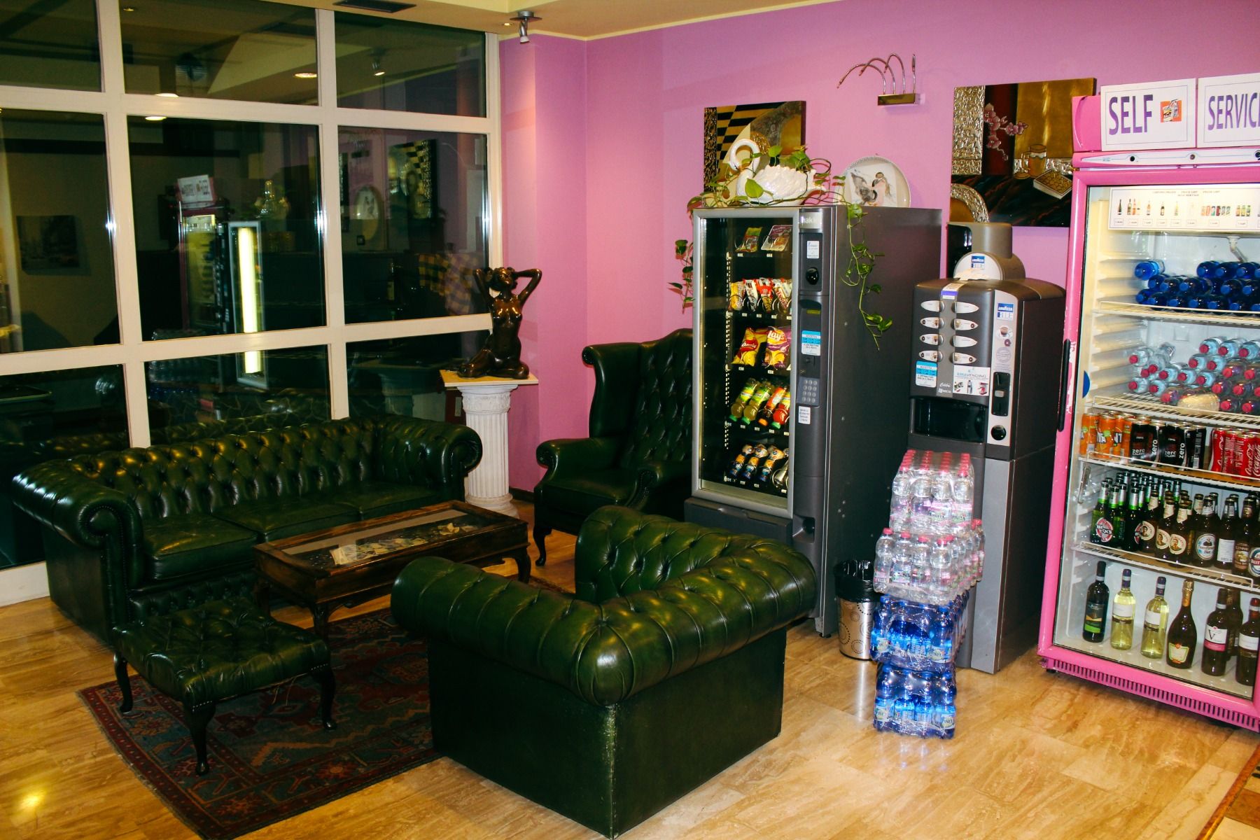 Gemütliche Lounge mit dunkelgrünen Ledersofas, Getränkeautomaten und dekorativer Einrichtung, ideal zum Entspannen