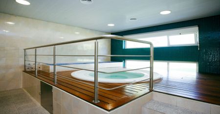 Helles Hotelzimmer mit zwei Betten mit einer roten Tagesdecke. Zudem eine Treppe, die zu einer zweiten Ebene im Zimmer führt.