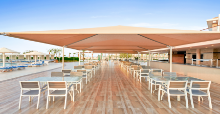 Aqua Vista Resort offers multiple outdoor pools, sun loungers, and umbrellas beneath clear blue skies—perfect for ein erfolgreiches Trainingslager in den Wintermonaten—with buildings and the sea in the background.