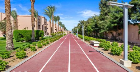 Aqua Vista Resort offers multiple outdoor pools, sun loungers, and umbrellas beneath clear blue skies—perfect for ein erfolgreiches Trainingslager in den Wintermonaten—with buildings and the sea in the background.