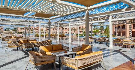 Aqua Vista Resort offers multiple outdoor pools, sun loungers, and umbrellas beneath clear blue skies—perfect for ein erfolgreiches Trainingslager in den Wintermonaten—with buildings and the sea in the background.