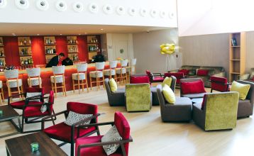 Außenansicht des Hotels mit Balkonen und einem großzügigen Poolbereich mit Liegestühlen und Holzboden.