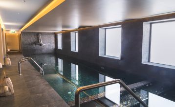 Außenansicht eines modernen Hotelgebäudes mit Balkonen und einem begrünten Vorgarten.