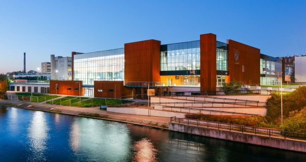 Außenansicht des modernen Gebäudes des Hotel Zawisza am Abend, beleuchtet am Wasserufer.