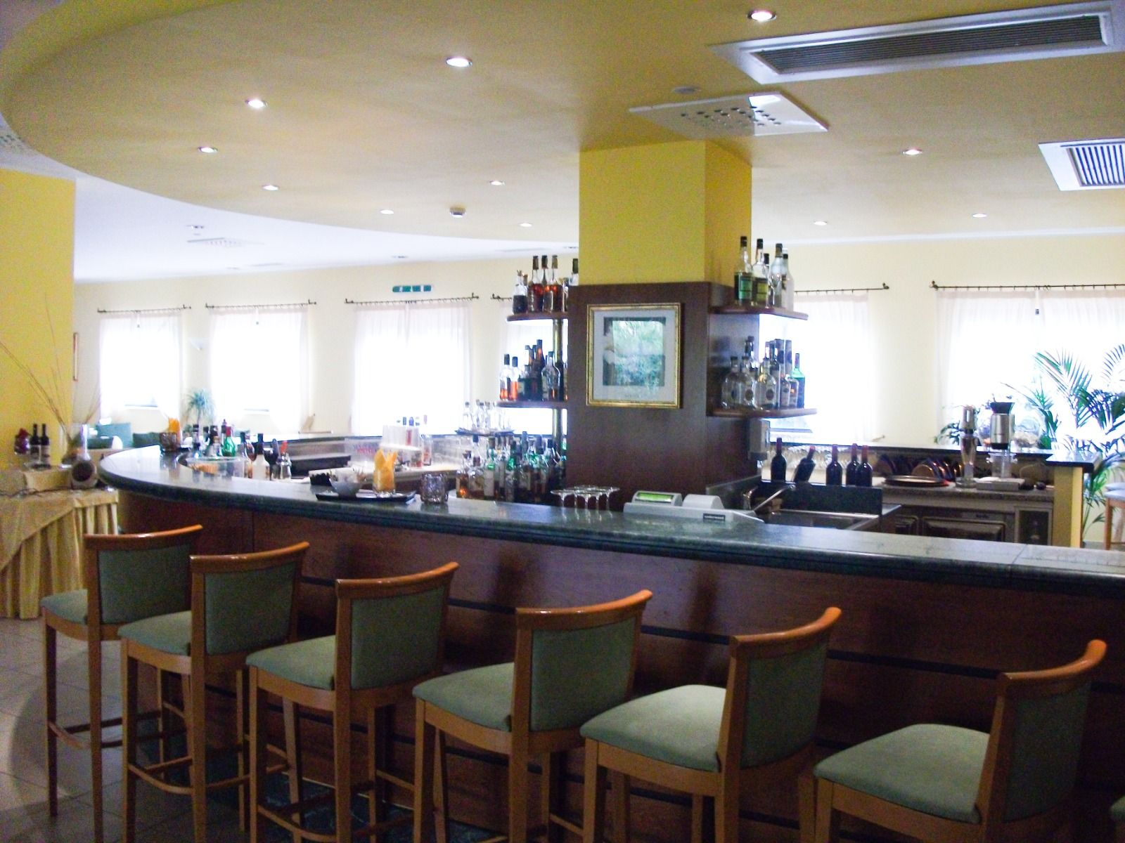 Elegante Hotelbar mit runder Theke, hohen Barhockern und gut beleuchtetem Innenbereich, ideal für einen Drink am Abend