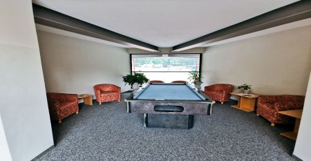 Außenansicht des Sporthotel Kapfenberg mit moderner Fassade und Hotelbeschriftung, im Hintergrund eine Burg auf einem Hügel