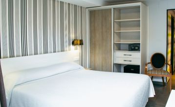 Das moderne New Hotel Colon mit mehreren Stockwerken, Balkonen und einer gepflegten Fassade, umgeben von grünen Bäumen und urbaner Architektur.