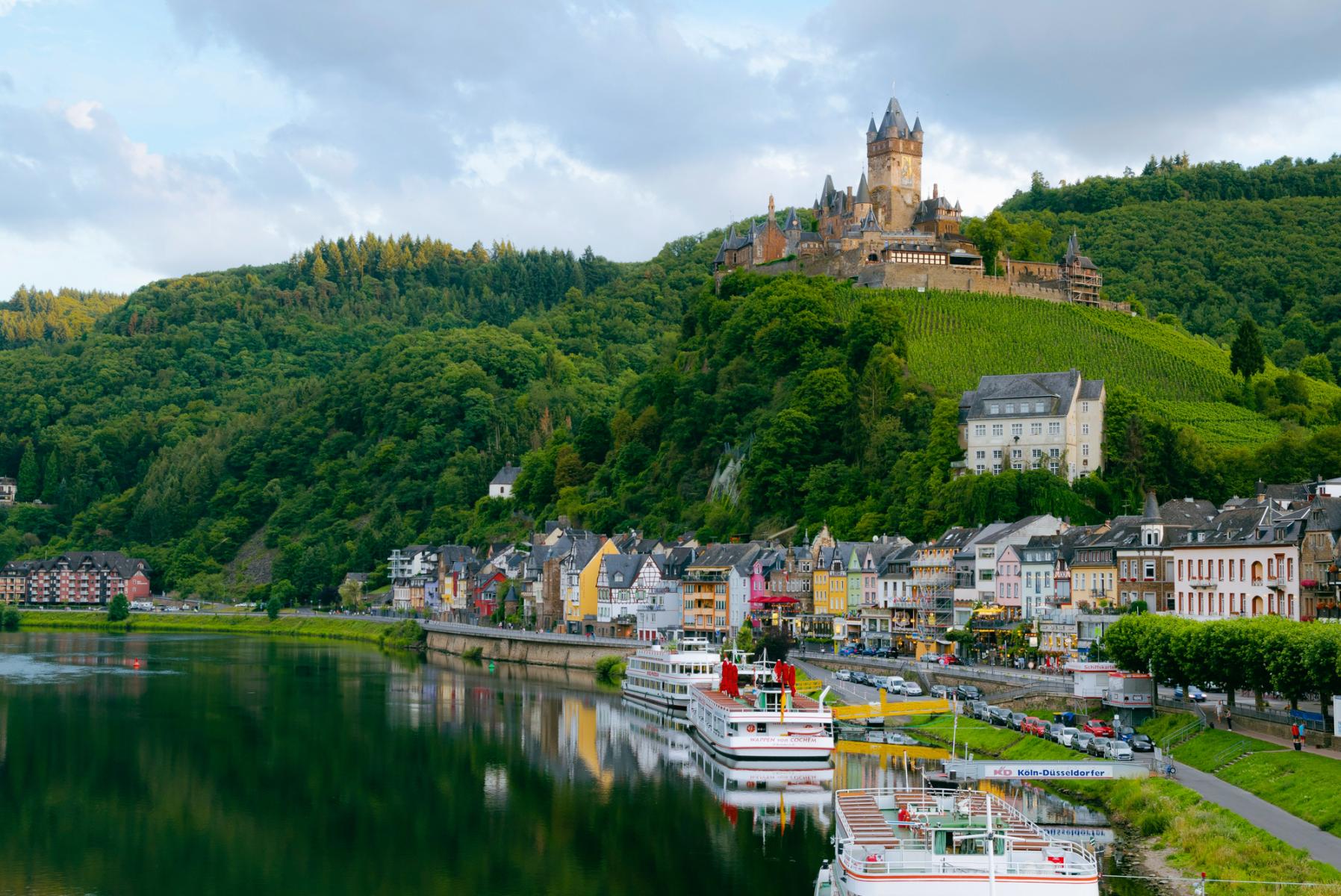 Fluss neben Häusern und einem Berg mit Burg