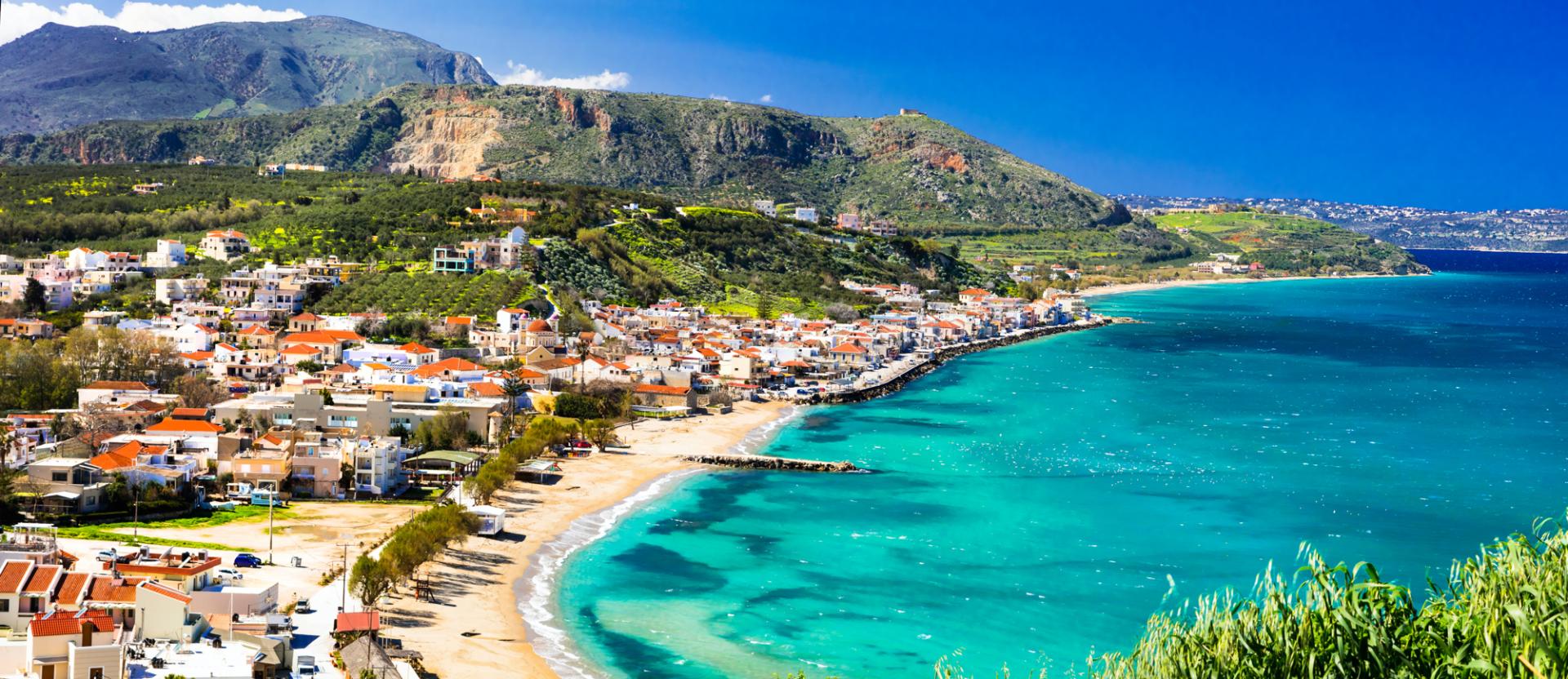 Blick von oben auf Sandstrand mit türkisblauem Meer an einer griechischen Küste