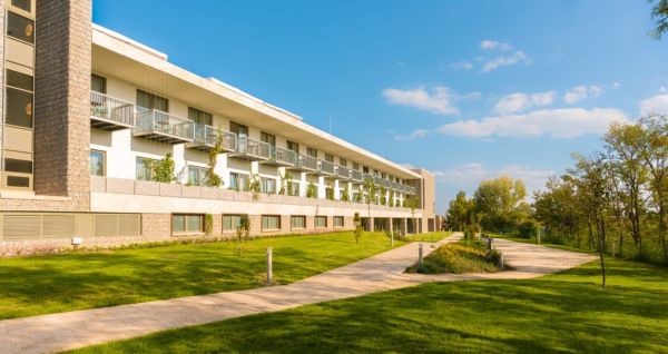 Außenansicht des Hotels Akademia mit gepflegtem Garten und modernen Balkonen. Sonniger Tag und einladende Atmosphäre.