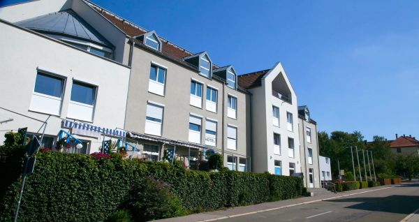 Außenansicht des Hotel im Kaiserpark in Meiningen, Thüringen, neben einer Straße mit einer grünen Hecke und blauem Himmel