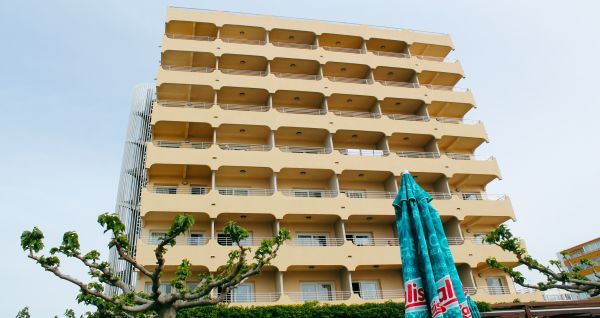Außenansicht des Hotel Victoria mit einer modernen, mehrstöckigen Fassade und Balkonen, umgeben von Grünanlagen.
