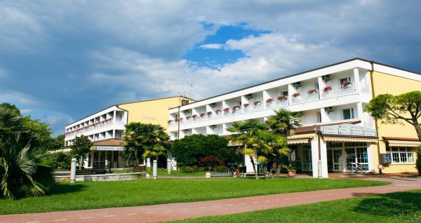 Außenansicht des Hotel Pra Delle Torri mit viel Grün und zwei Stockwerken mit Balkonen darunter der Eingang und das Restaurant
