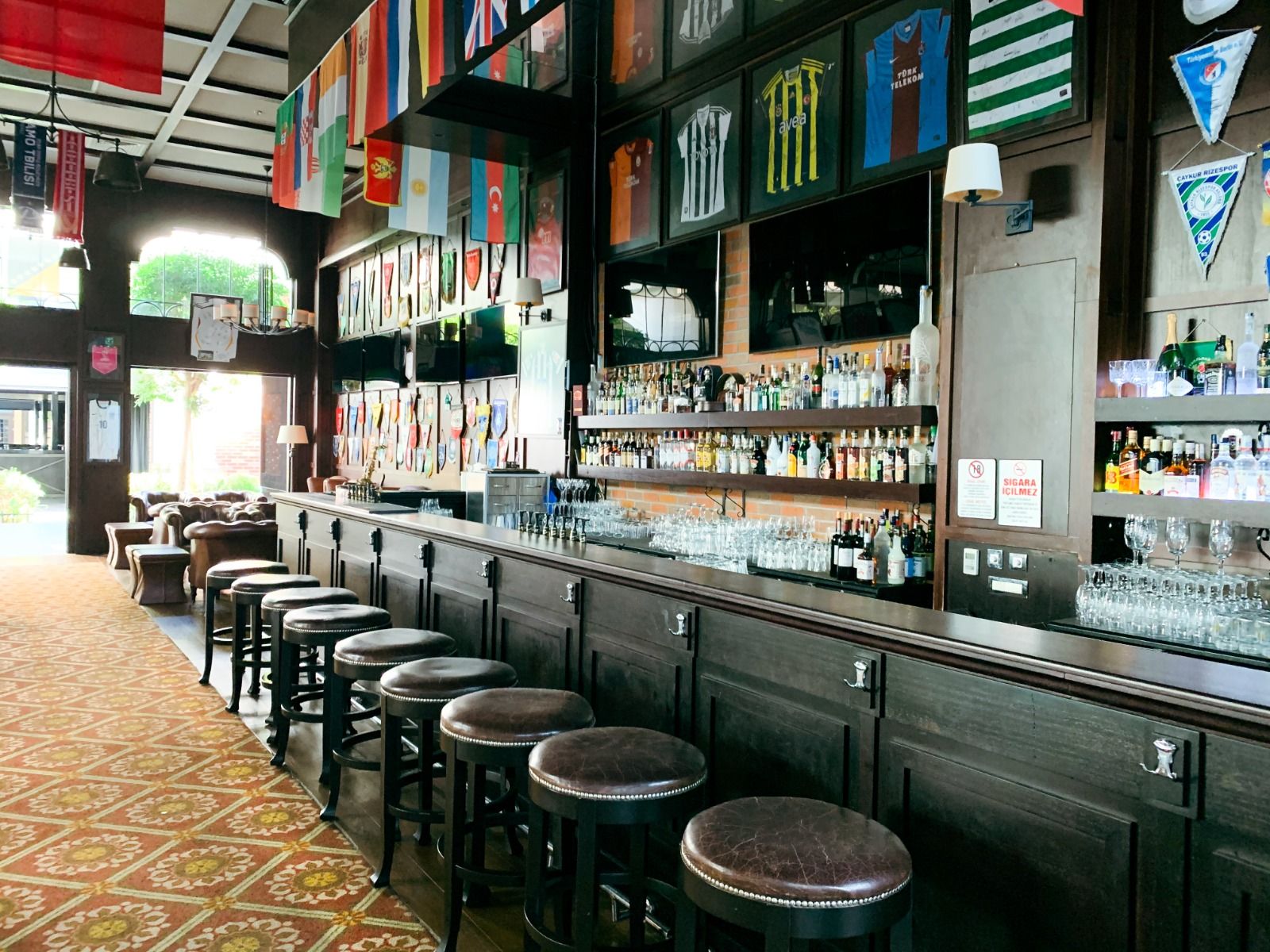 Schöne Bar mit internationaler Flaggen-Dekoration und gemütlichen Sitzmöglichkeiten.