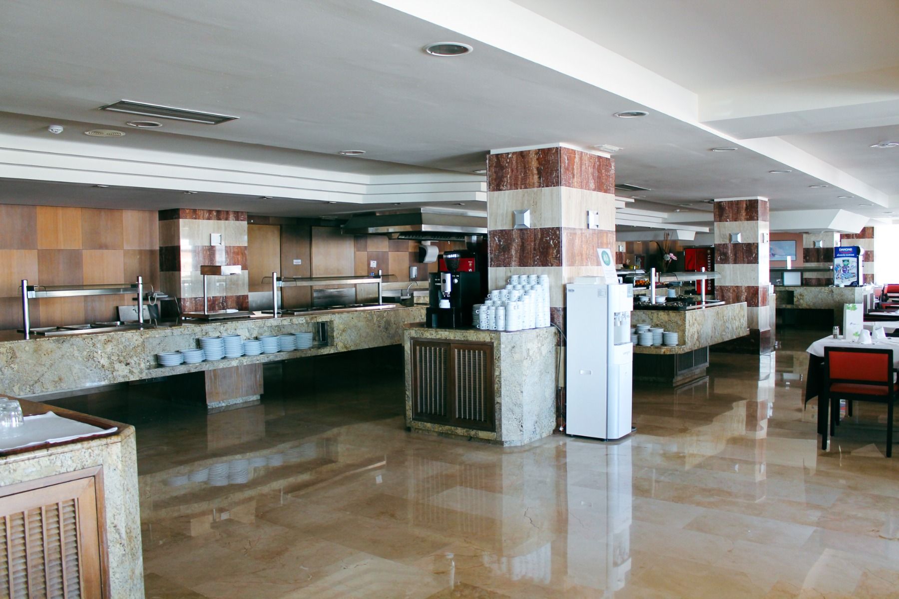 Ein heller und geräumiger Speisesaal mit modernen Buffetstationen aus Marmor und einer stilvollen Inneneinrichtung, die Sauberkeit und Eleganz vermittelt.