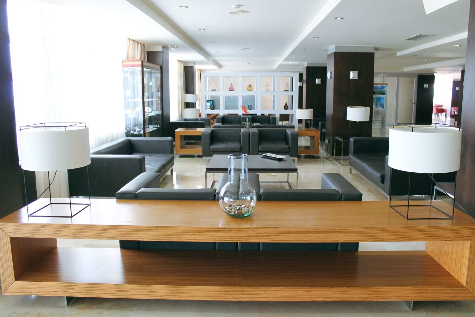 Eine schicke und minimalistisch eingerichtete Hotel-Lobby mit modernen Ledersofas, stilvollen Lampen und einer eleganten Dekoration, die eine warme und einladende Atmosphäre schafft.