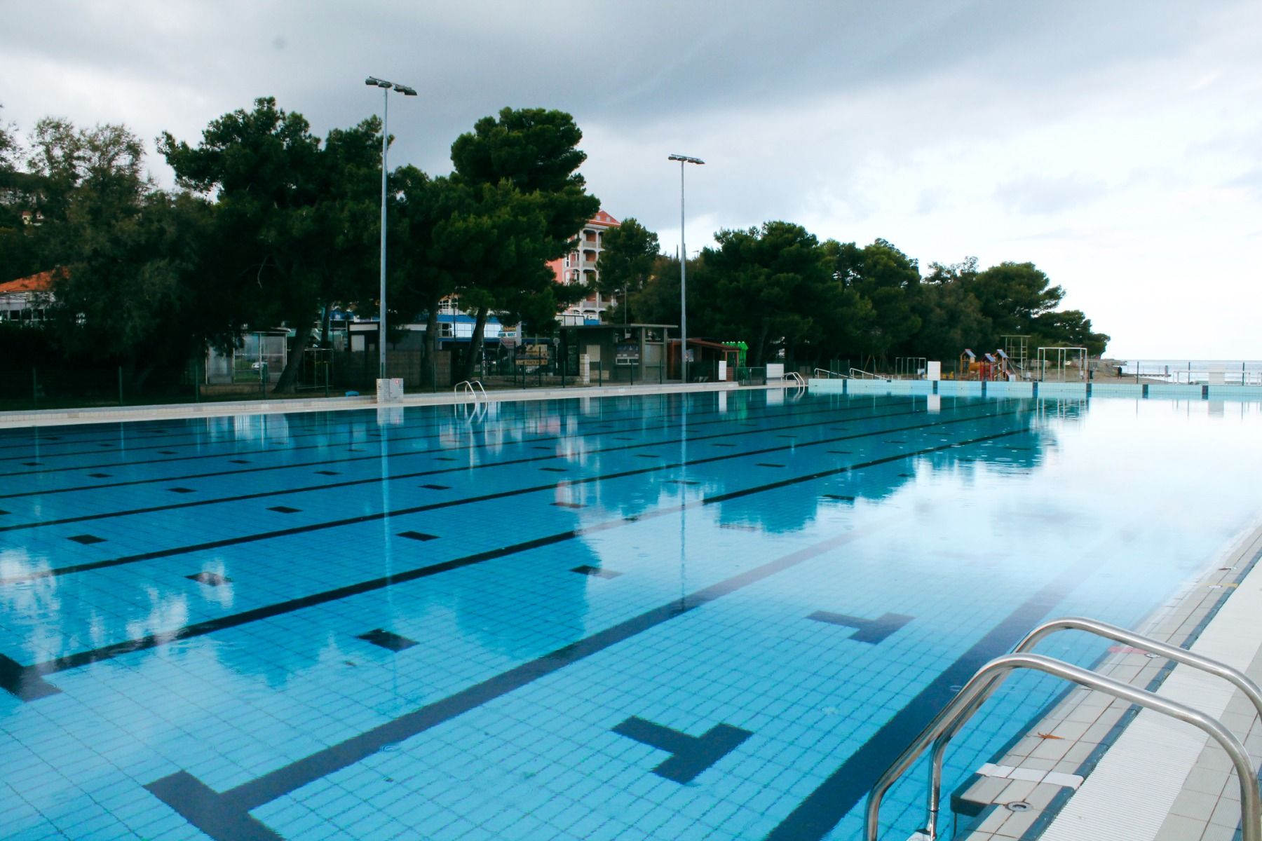 Freiluft-Schwimmbereich des Hotels mit olympischen Bahnen und angrenzender Vegetation.