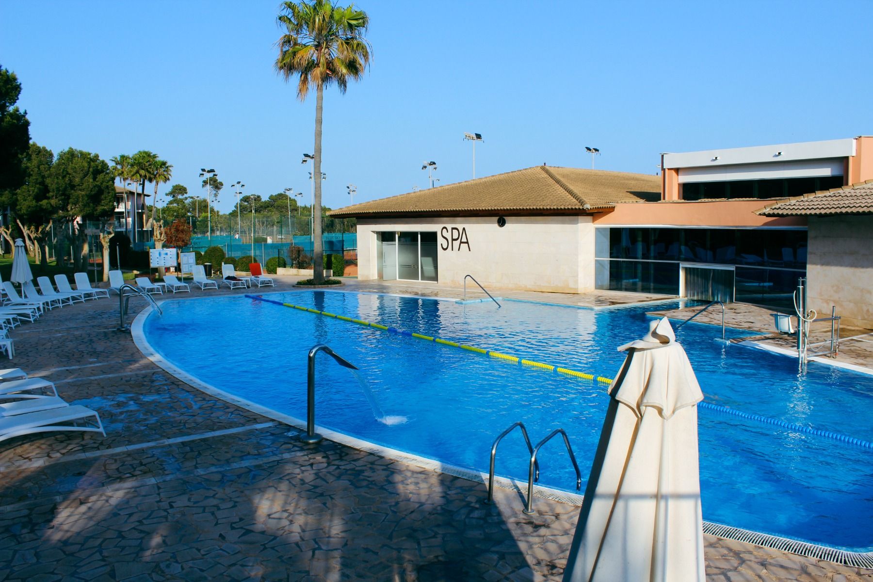 Poolbereich des Hotels Blau Club mit einem großen Schwimmbecken, Liegestühlen und einem angrenzenden Spa-Bereich.