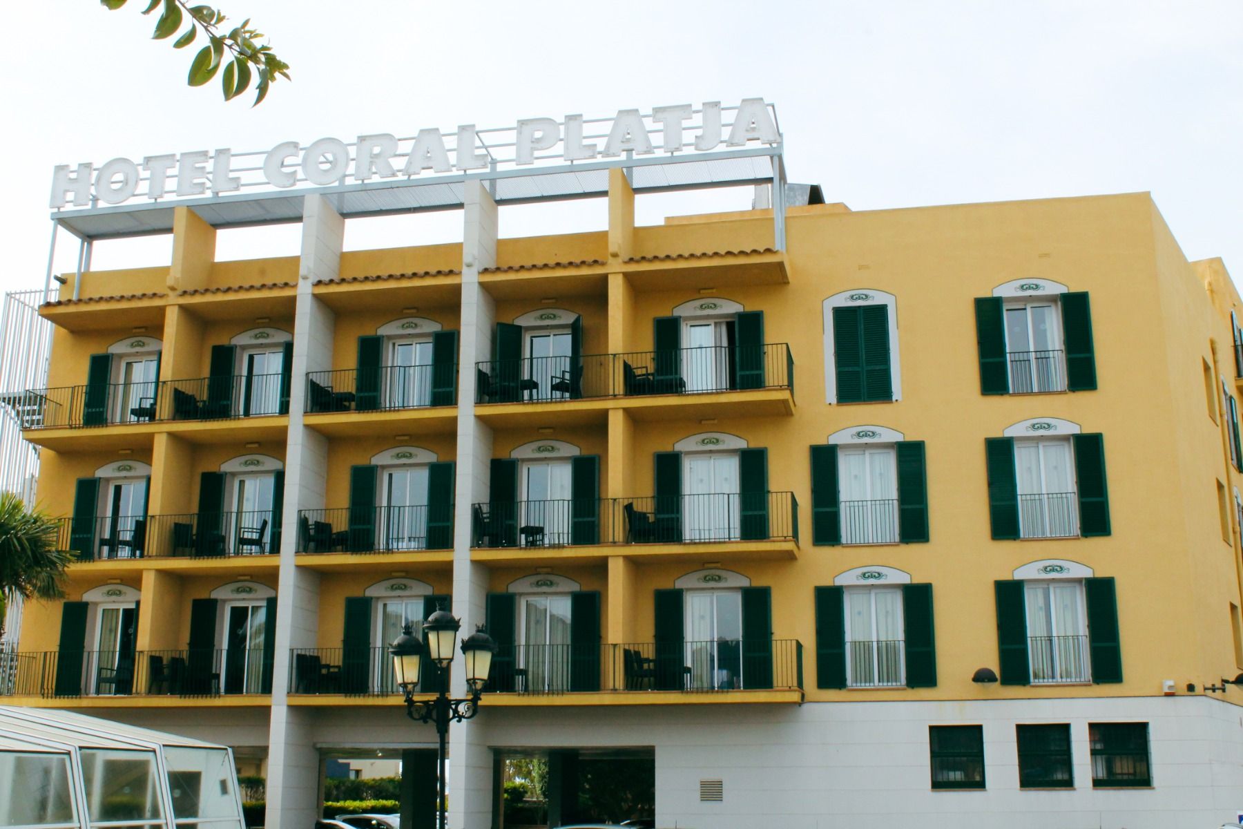 Außenansicht des Hotels Coral Platja am Tag mit Schriftzug und Balkonen.