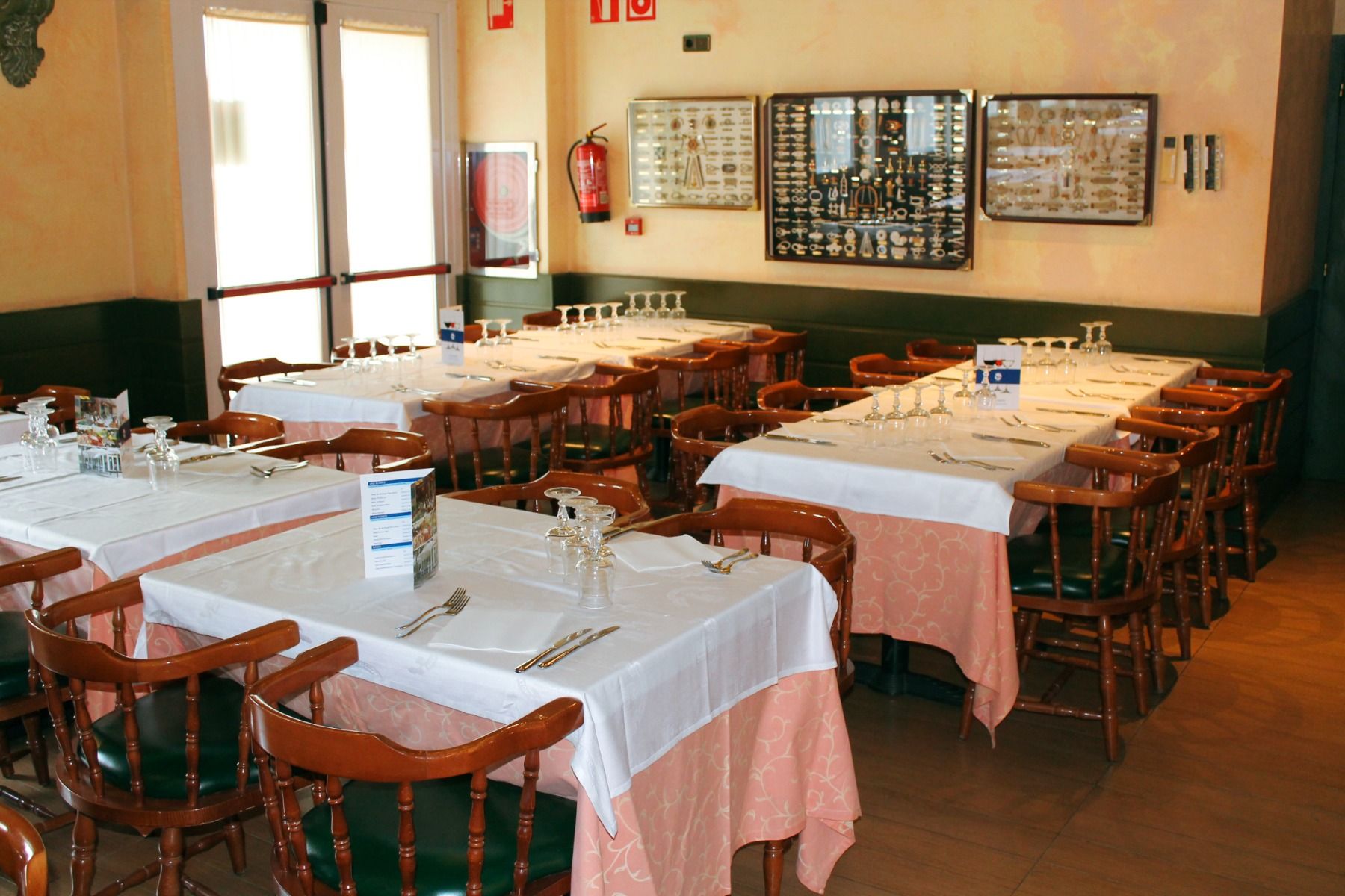 Restaurant des Hotels Coral Platja mit gedeckten Tischen und Holzstühlen.