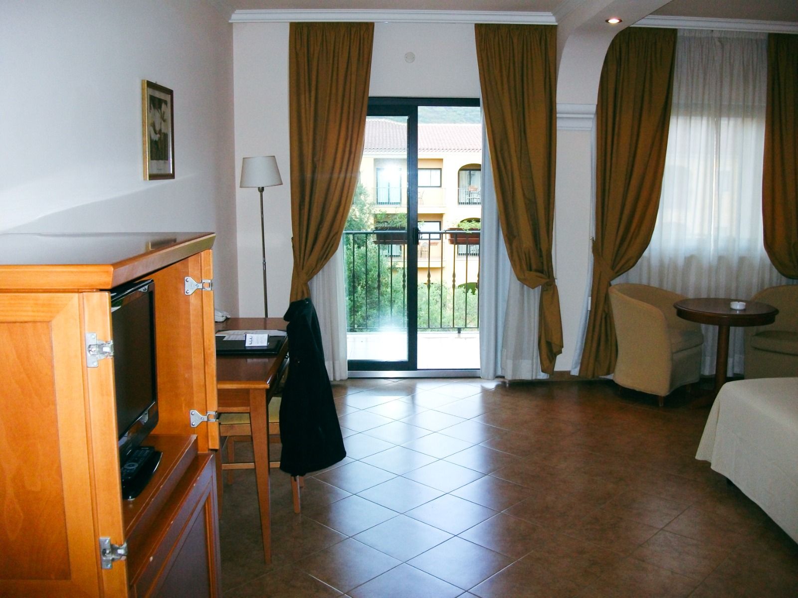 Doppelzimmer mit Balkon, Blick auf den Innenhof und einer Sitzecke mit eleganter Holzmöblierung