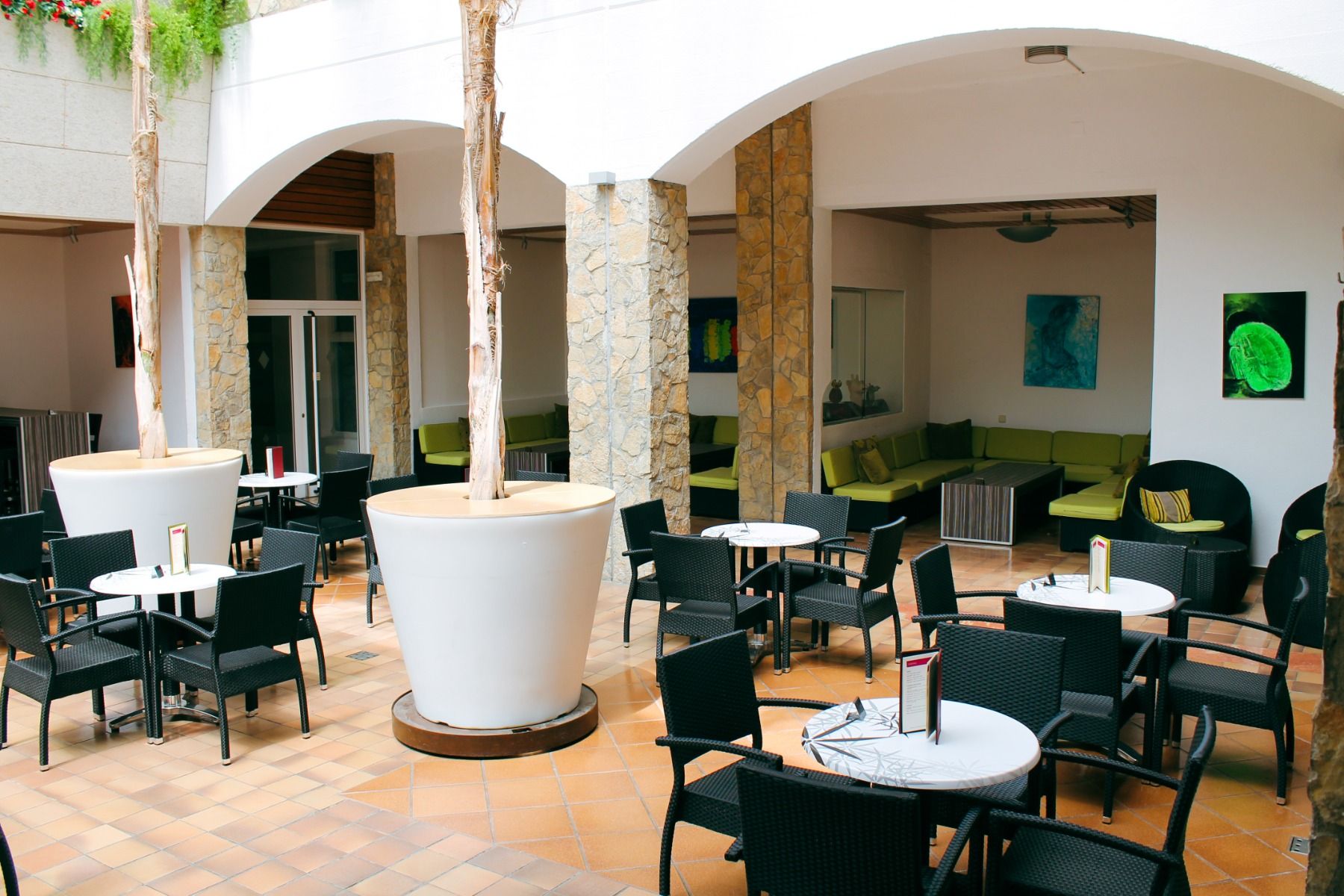 Lounge-Bereich im Innenhof mit modernen schwarzen Sitzmöbeln und großen weißen Pflanzgefäßen.