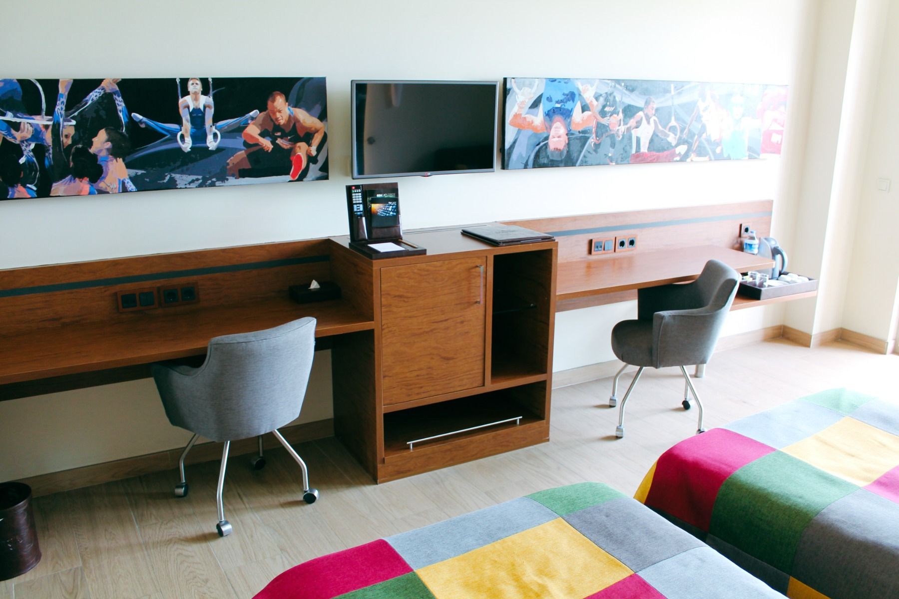 Schreibtischbereich in einem modernen Zimmer mit Wandbildern und Flachbildfernseher.