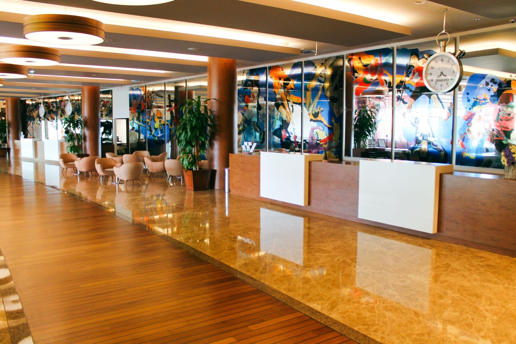 Großzügige Lobby mit Sport-Collagen an den Wänden, Empfangstresen und bequemen Sitzmöglichkeiten.