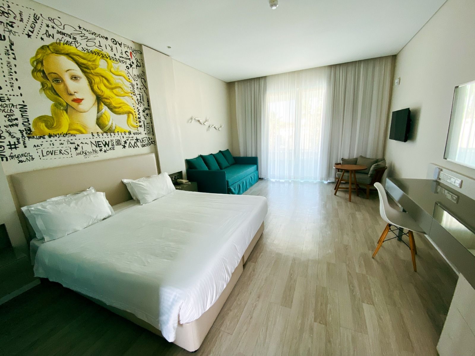 Großzügiges Hotelzimmer mit modernem Design, Kunst an der Wand und bodentiefen Fenstern. 