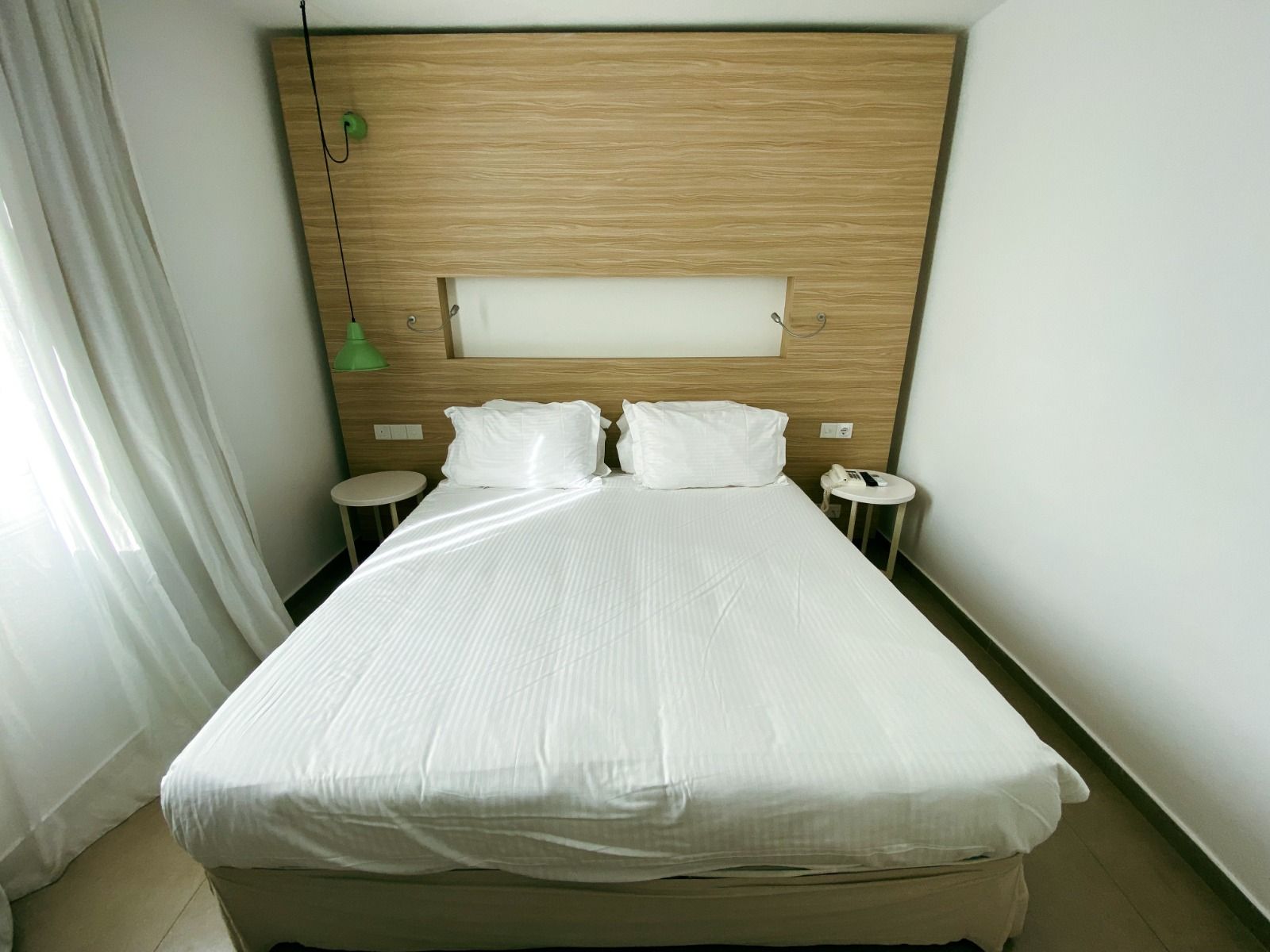 Helles Doppelzimmer mit Holzverkleidung, schlichten Möbeln und minimalistischer Dekoration. 