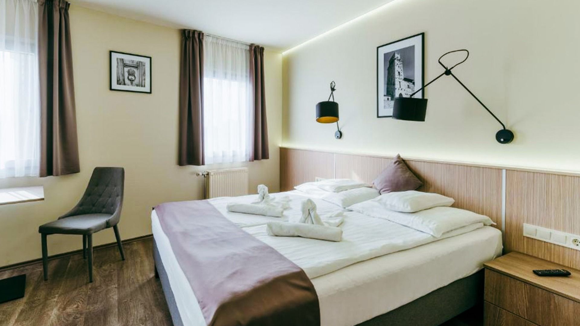 Helles und freundliches Hotelzimmer mit Doppelbett, stilvollen Wandleuchten und minimalistischer Einrichtung im Hotel Amstel Hattyu Fogado