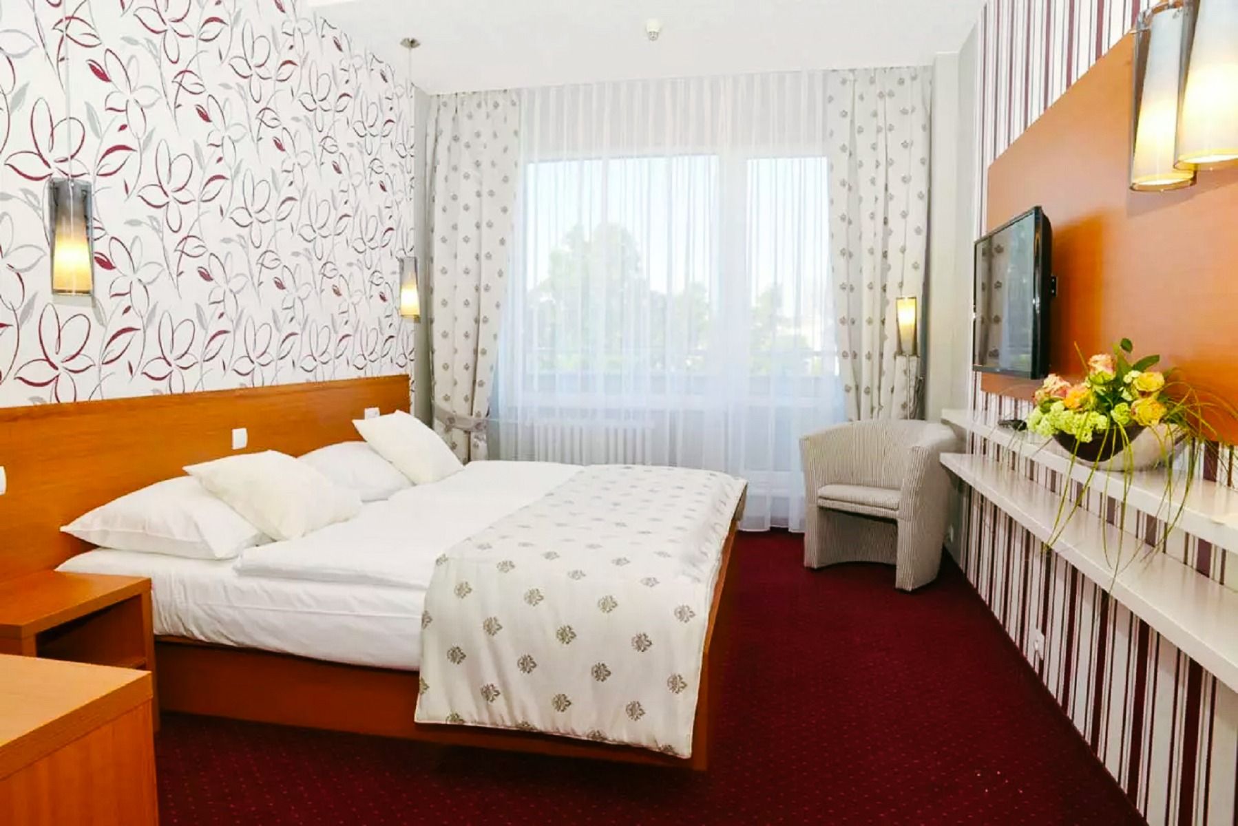 Ein geräumiges Zimmer mit einem breiten Doppelbett, luxuriöser Bettwäsche, einem Flachbild-TV und gemütlichen Sitzgelegenheiten.