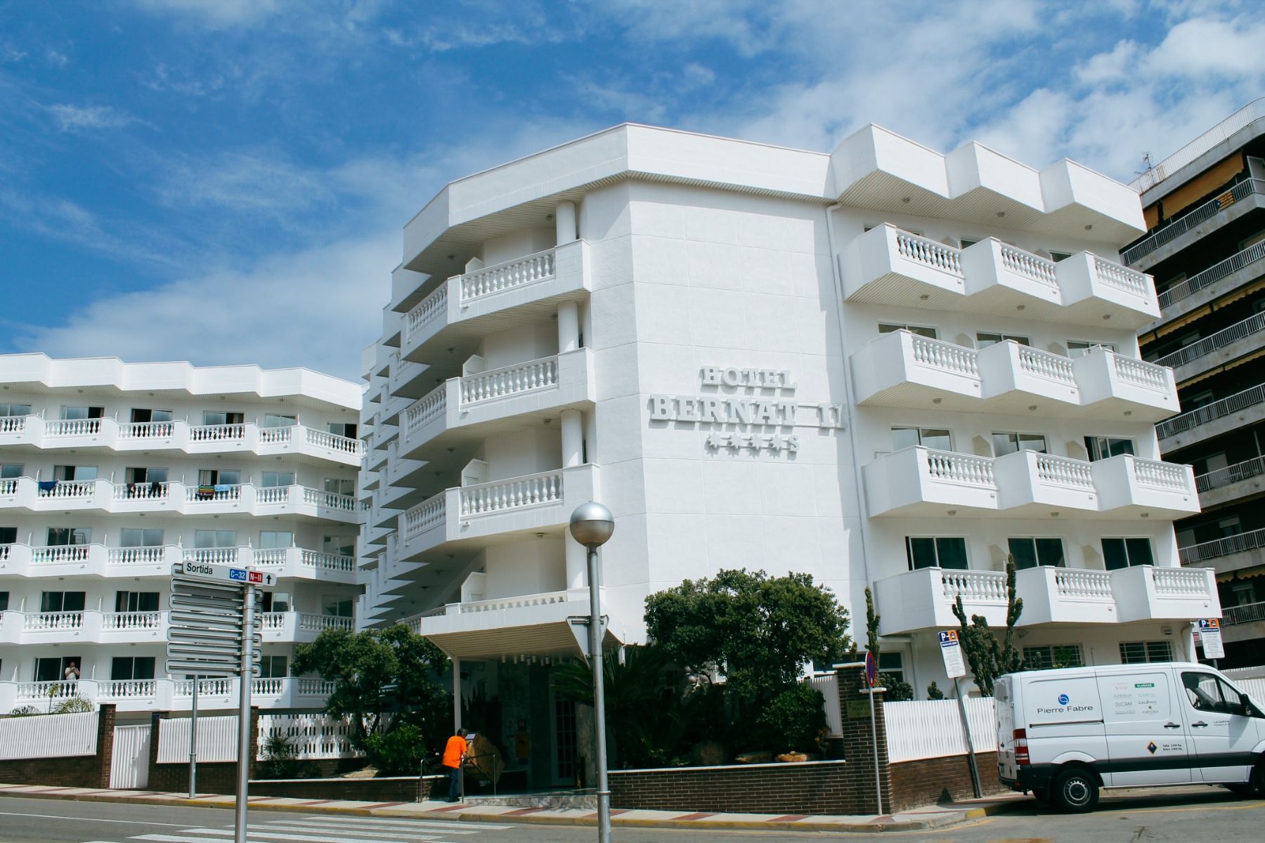 Außenansicht des Hotels Bernat II, ein weißes Gebäude mit Balkonen unter einem blauen Himmel.