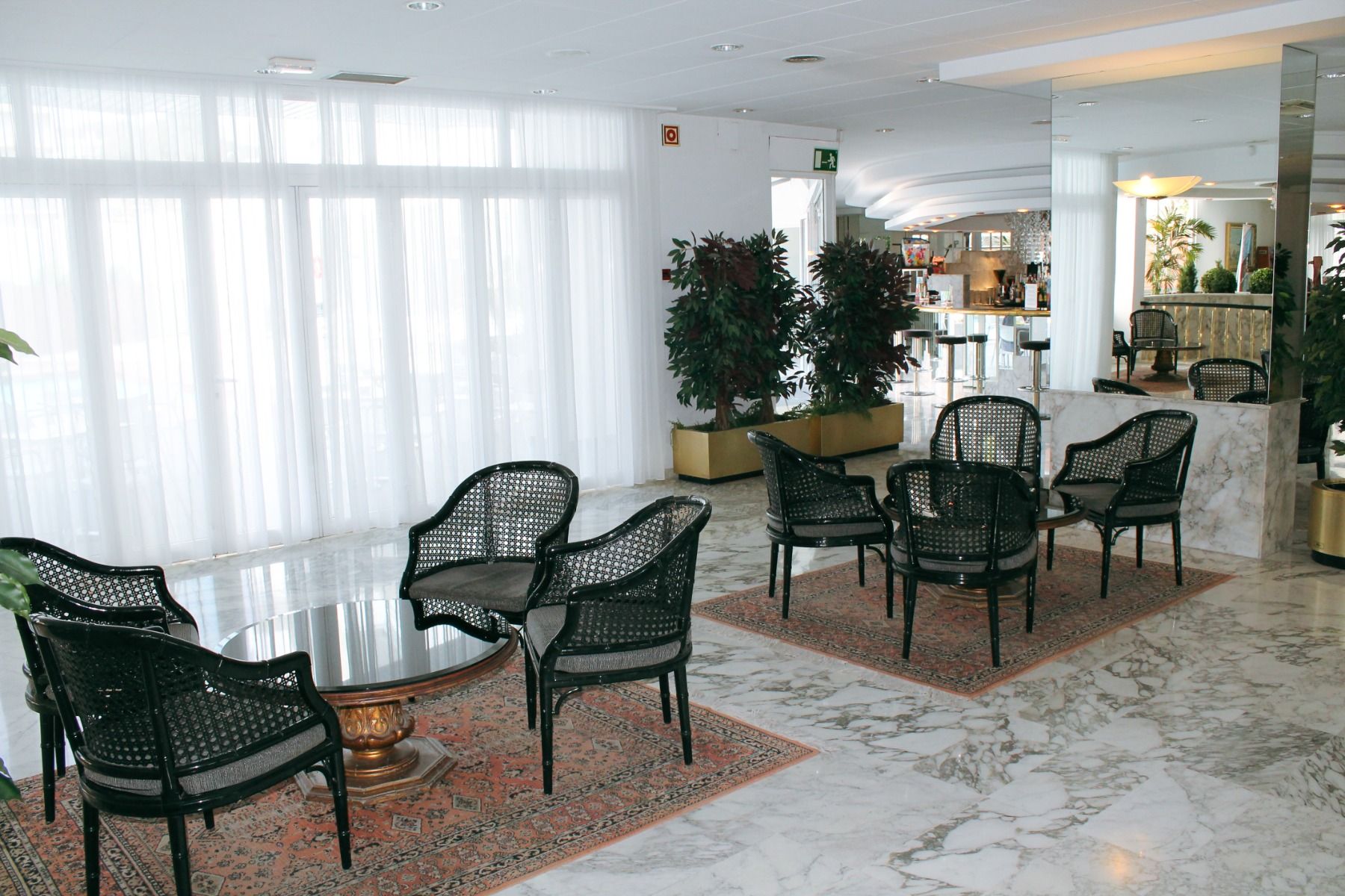 Elegante Hotel-Lobby mit Marmorboden, Sitzgruppen und großen Fenstern.