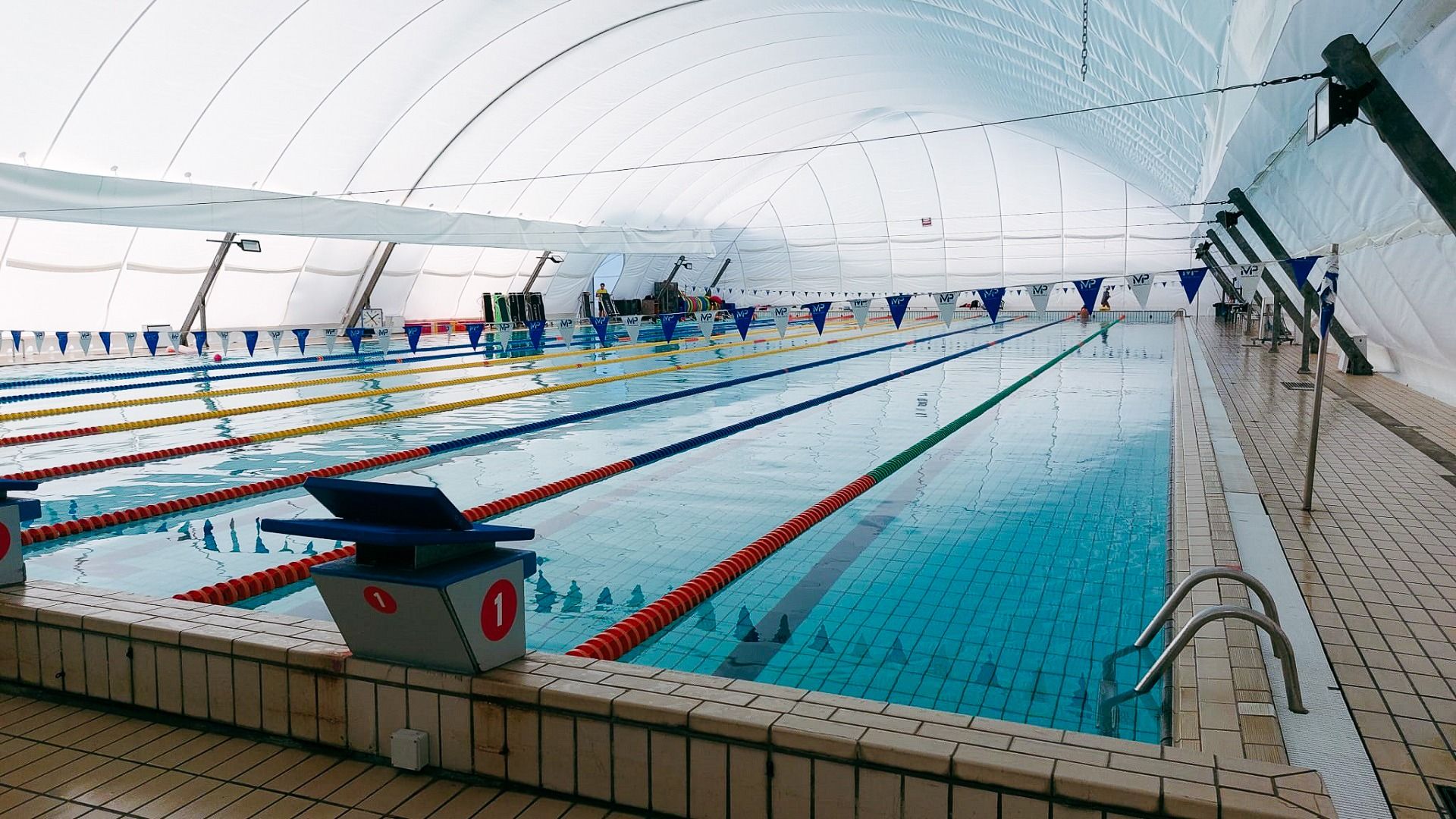 Großes, professionelles Schwimmbecken mit Traglufthalle und mehreren Bahnen und Startblöcken