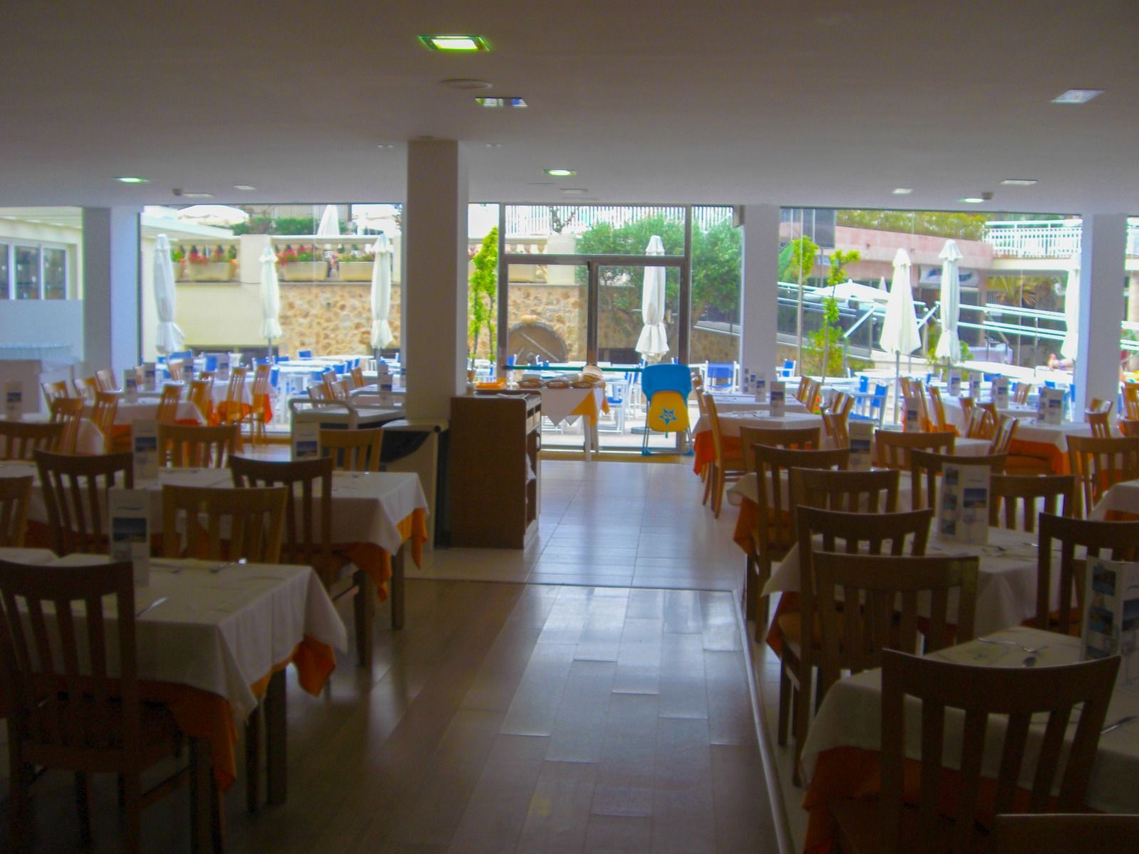 Restaurantbereich des Hotels Janeiro mit gedeckten Tischen, Blick auf die Terrasse und den Pool.