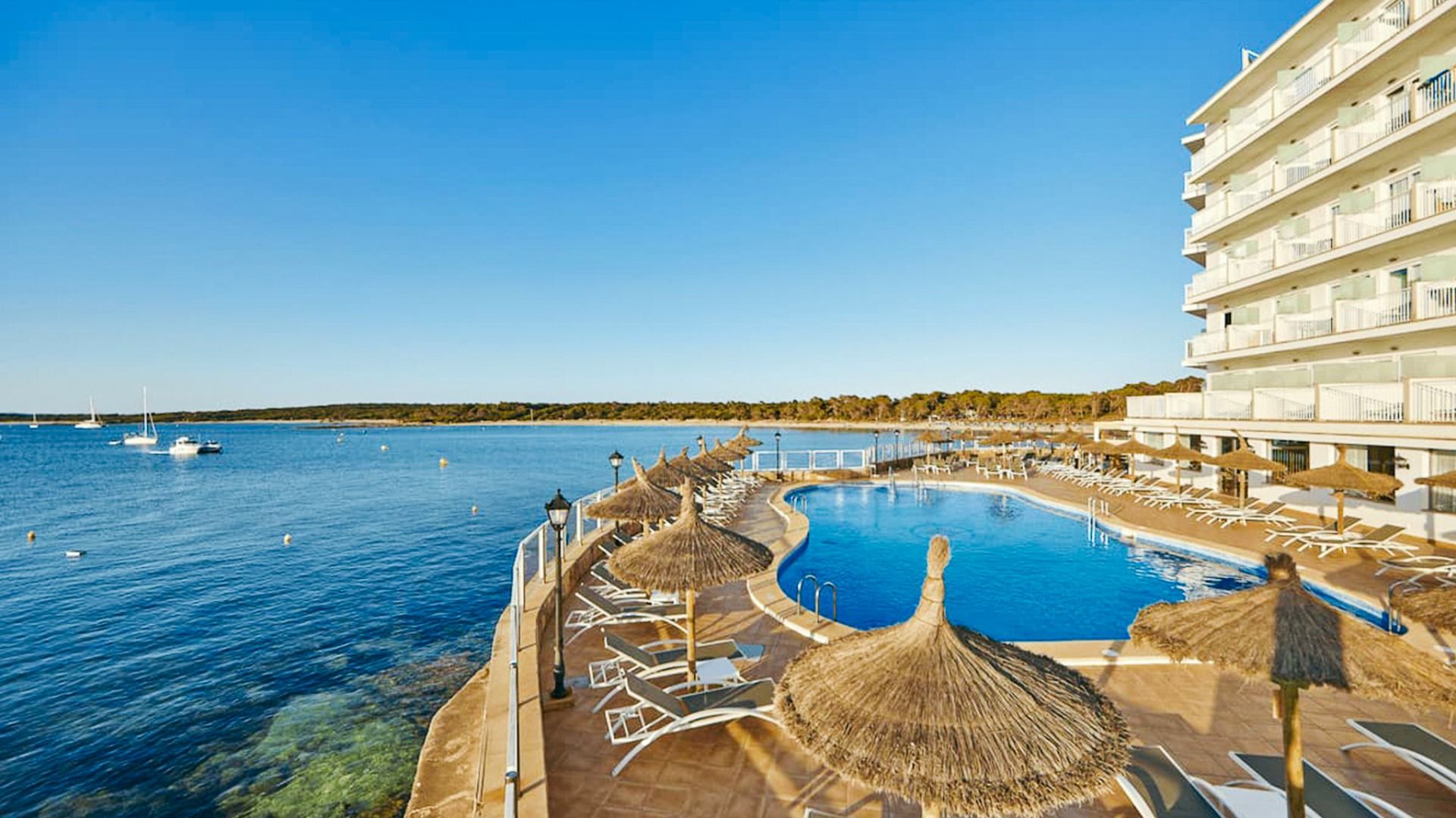 Poolbereich des Hotel Marqués direkt am Meer mit Sonnenschirmen, Liegestühlen und herrlicher Aussicht auf das Mittelmeer