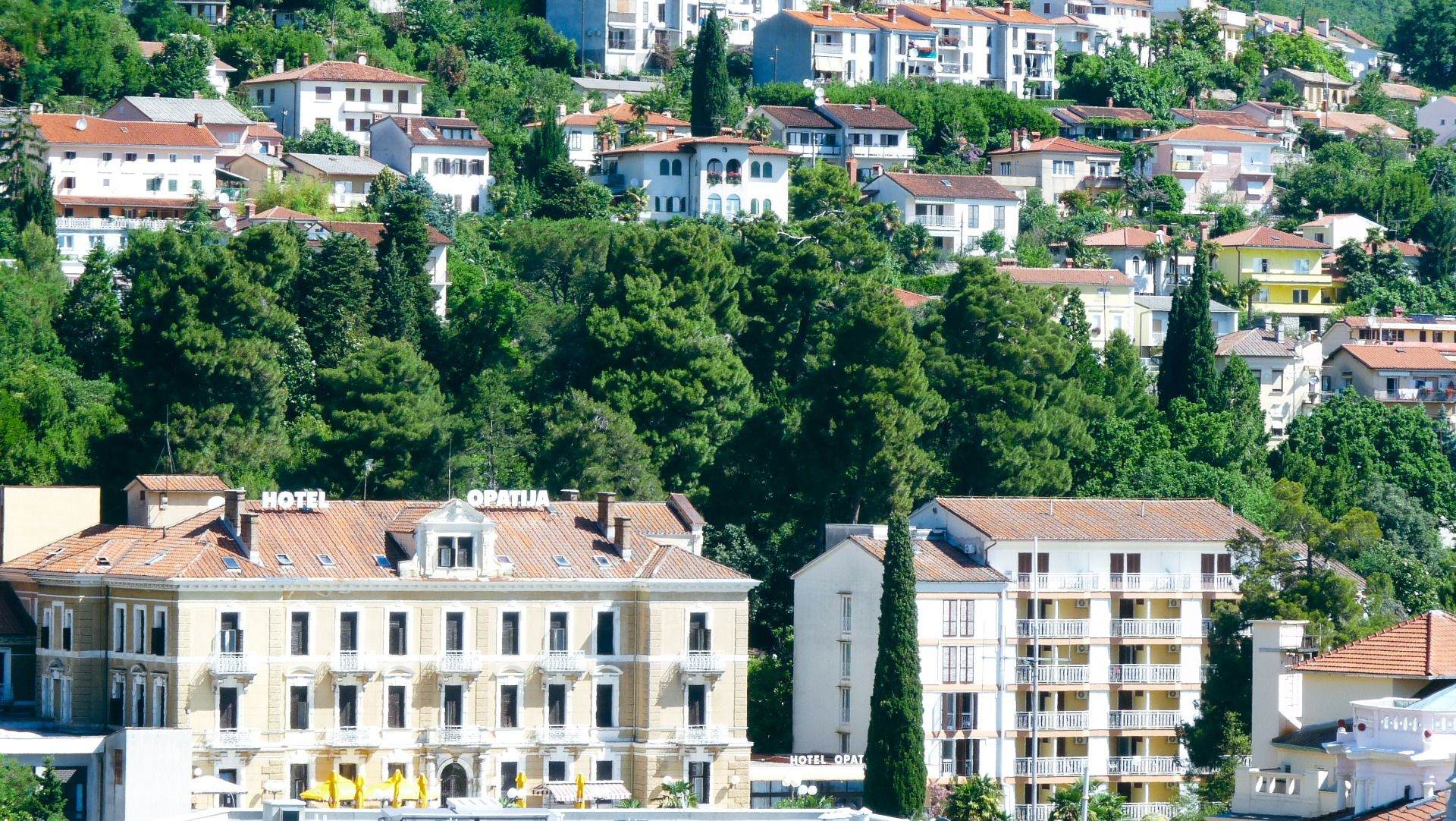 Eine Gesamtansicht des Hotels Opatija, eingebettet in grüne Hügel mit umliegenden Gebäuden und Vegetation