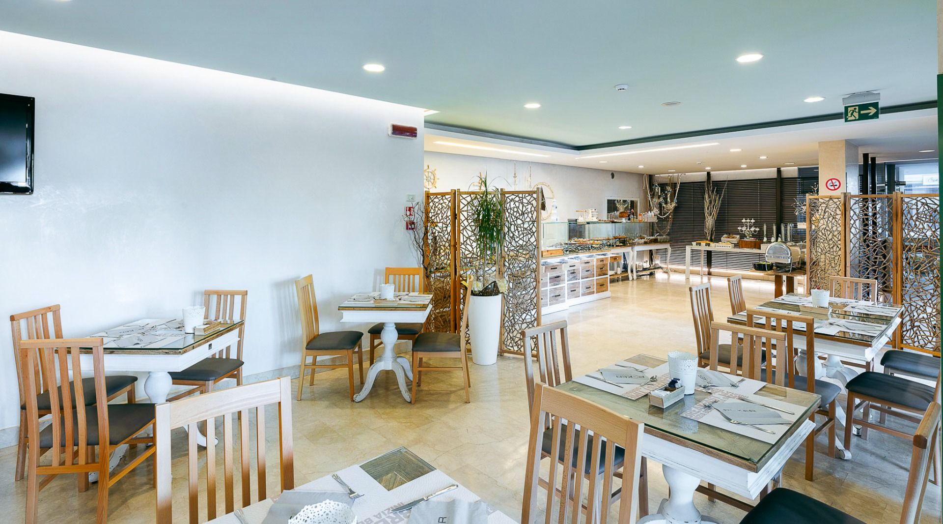 Frühstücksbereich im Hotel Poker in Riccione, Italien, mit modernem Interieur, Holzstühlen und Buffet im Hintergrund 