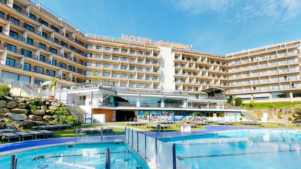 Außenansicht des Hotel Samba mit mehreren Etagen, Balkonen und einem großen Poolbereich in sonniger Umgebung.