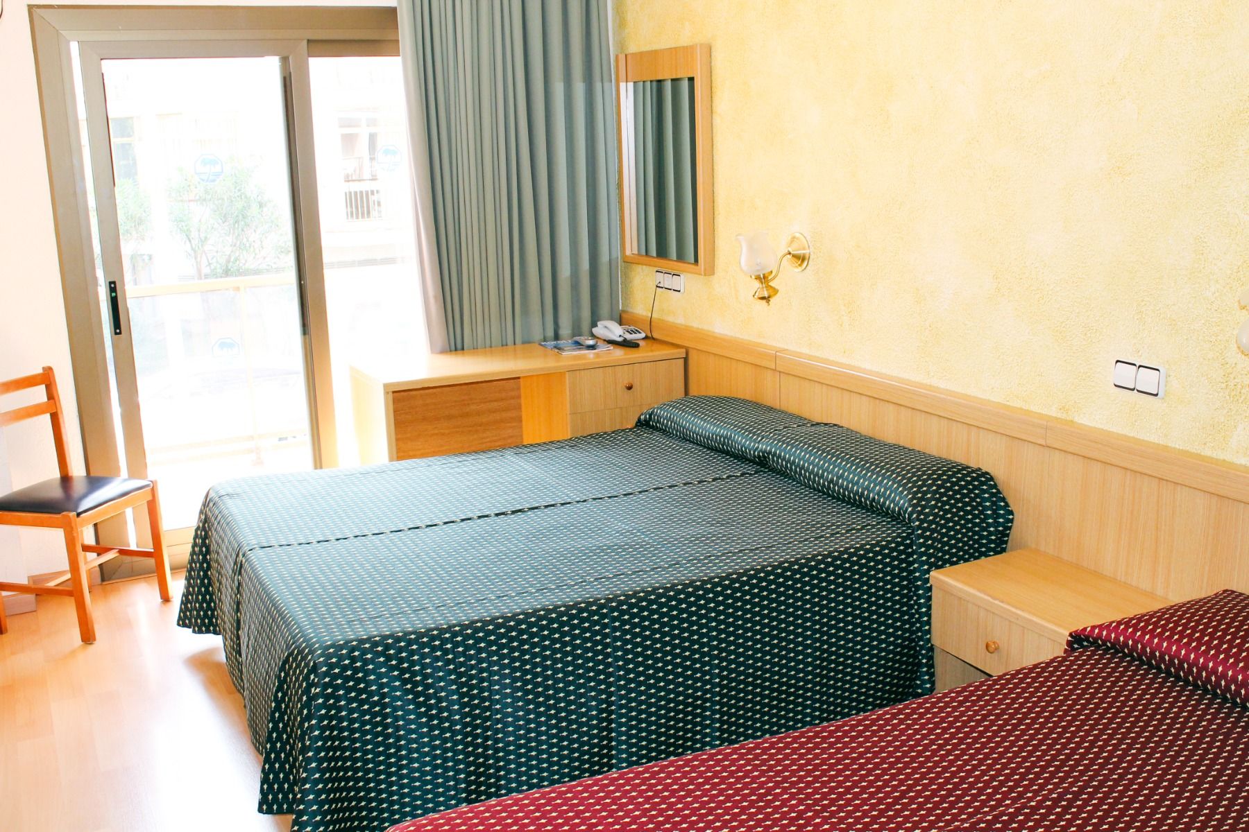 Ein gemütliches Hotelzimmer mit Holzmöbeln, zwei Betten und einem kleinen Schreibtisch.