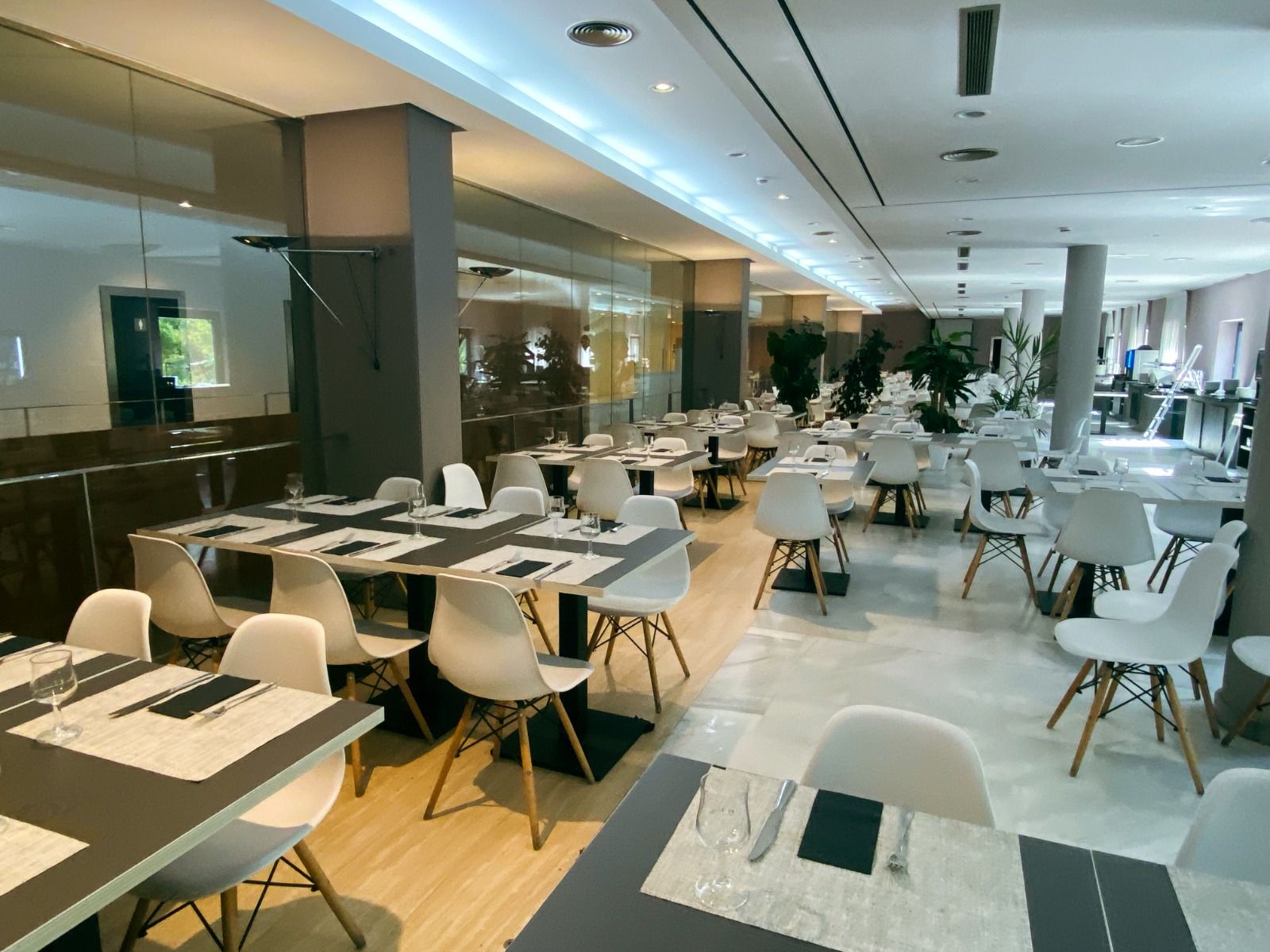 Modern eingerichtetes Hotelrestaurant mit eleganten weißen Stühlen, dunklen Tischen und einer stilvollen Beleuchtung.