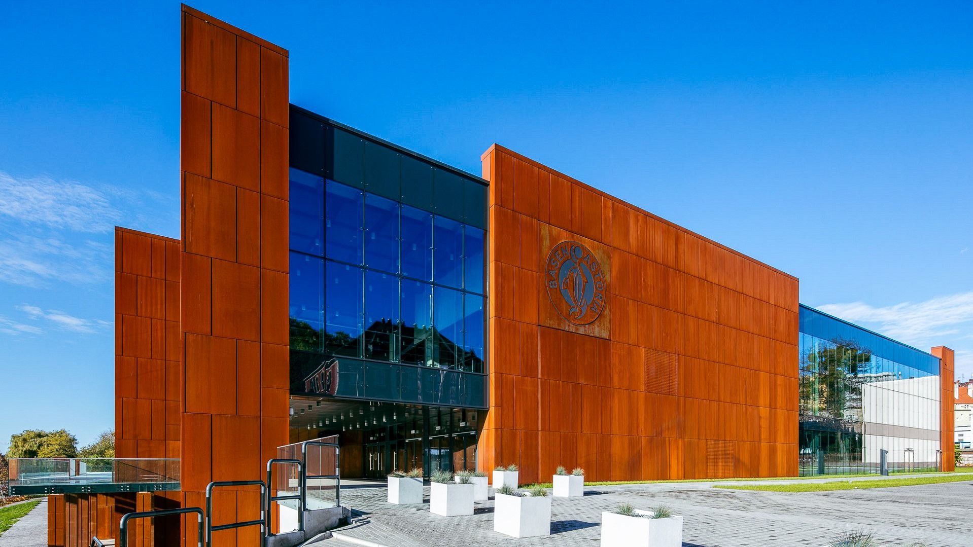 Architekturansicht des Eingangsbereichs vom Hotel Zawisza mit rostfarbenen Fassadenplatten und Glasfront.