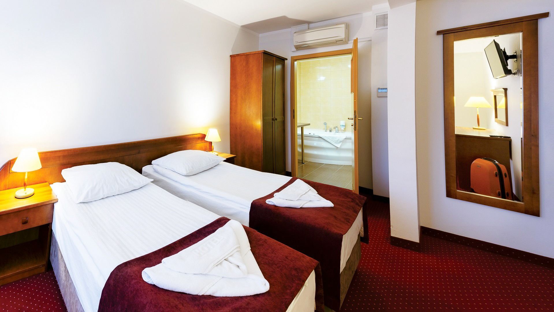 Hotelzimmer im Hotel Zawisza mit zwei Einzelbetten, Holzdekor und Zugang zu einem Badezimmer.
