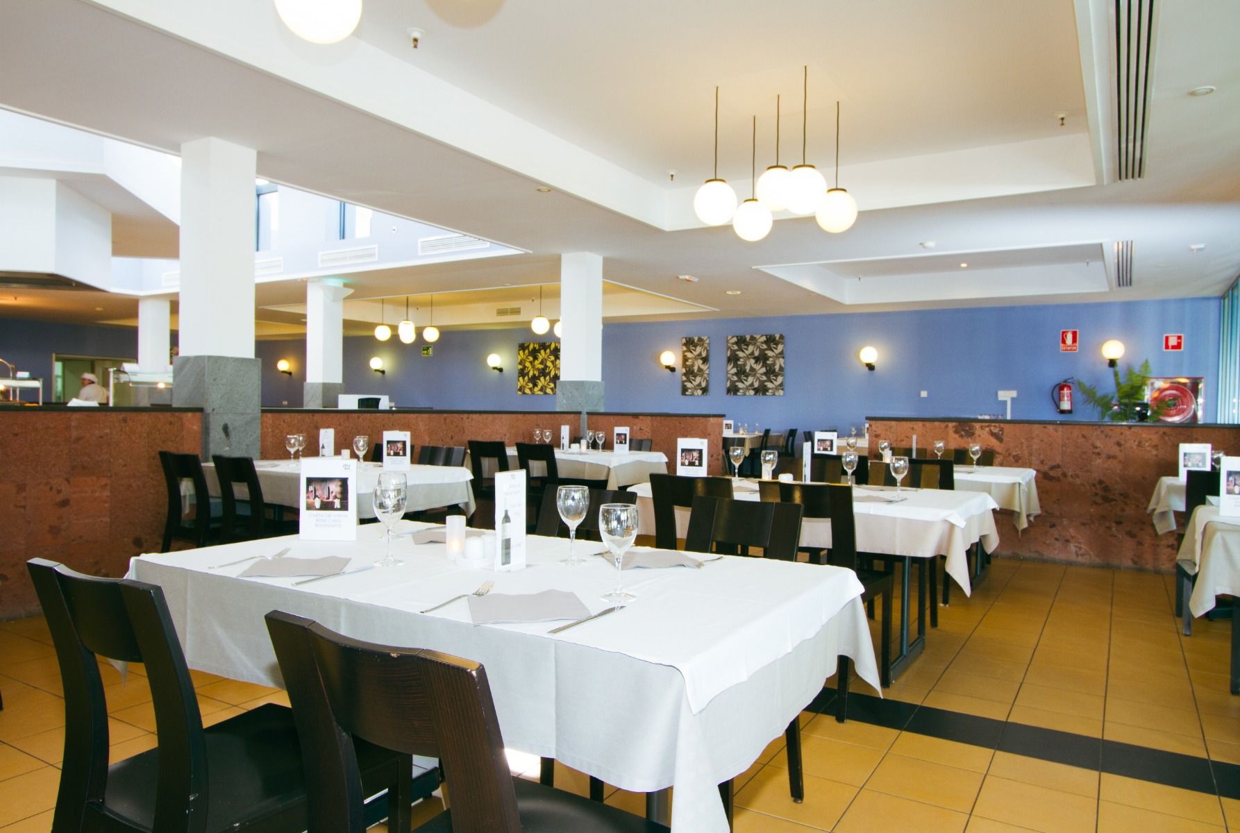 Ein elegantes Restaurant mit weiß eingedeckten Tischen, dunklen Stühlen und moderner Beleuchtung, das eine einladende Atmosphäre schafft.