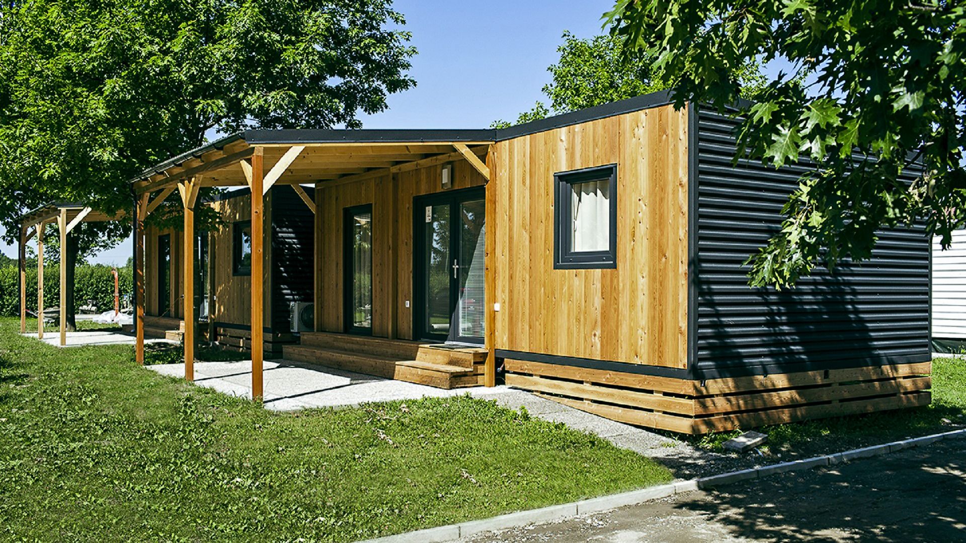 Außenansicht eines modernen Mobilheims mit Holzverkleidung und überdachter Terrasse im Mobile Homes Terme Ptuj.