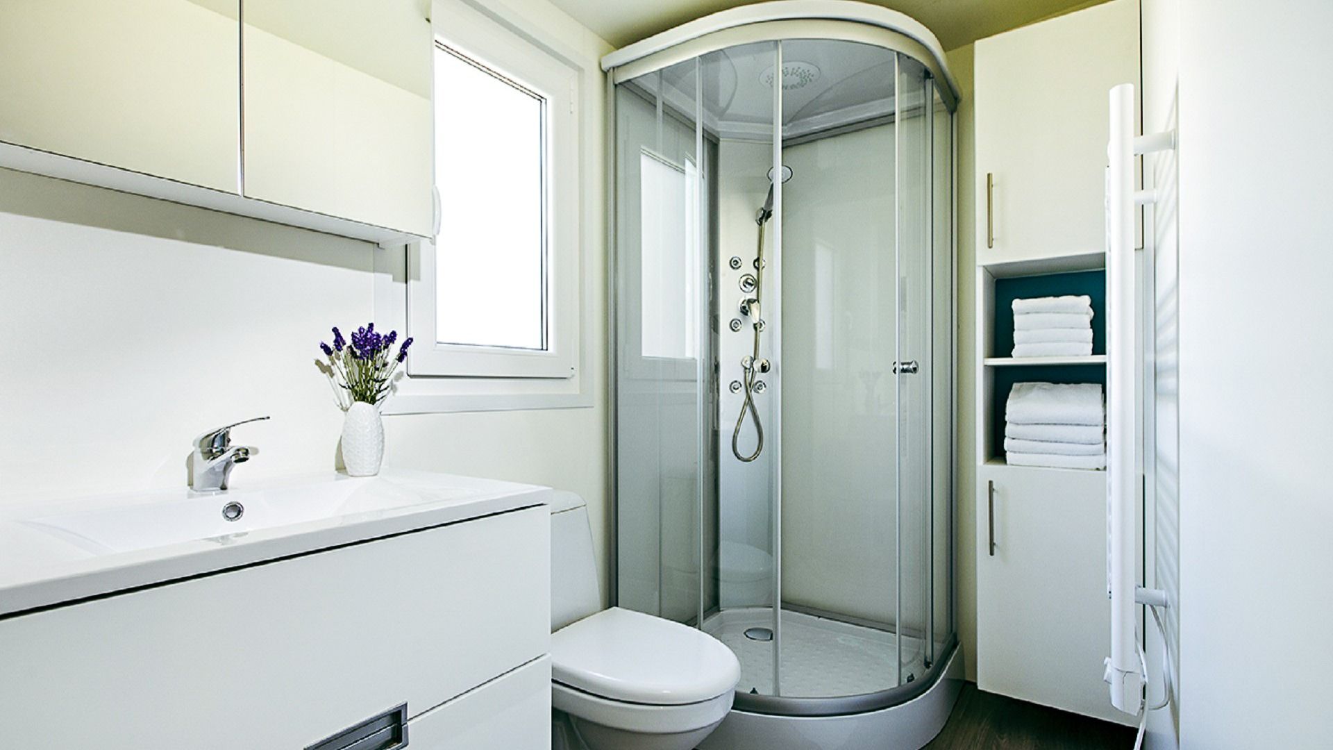 Modernes Badezimmer mit Glasdusche, weißen Handtüchern und eleganter Ausstattung.
