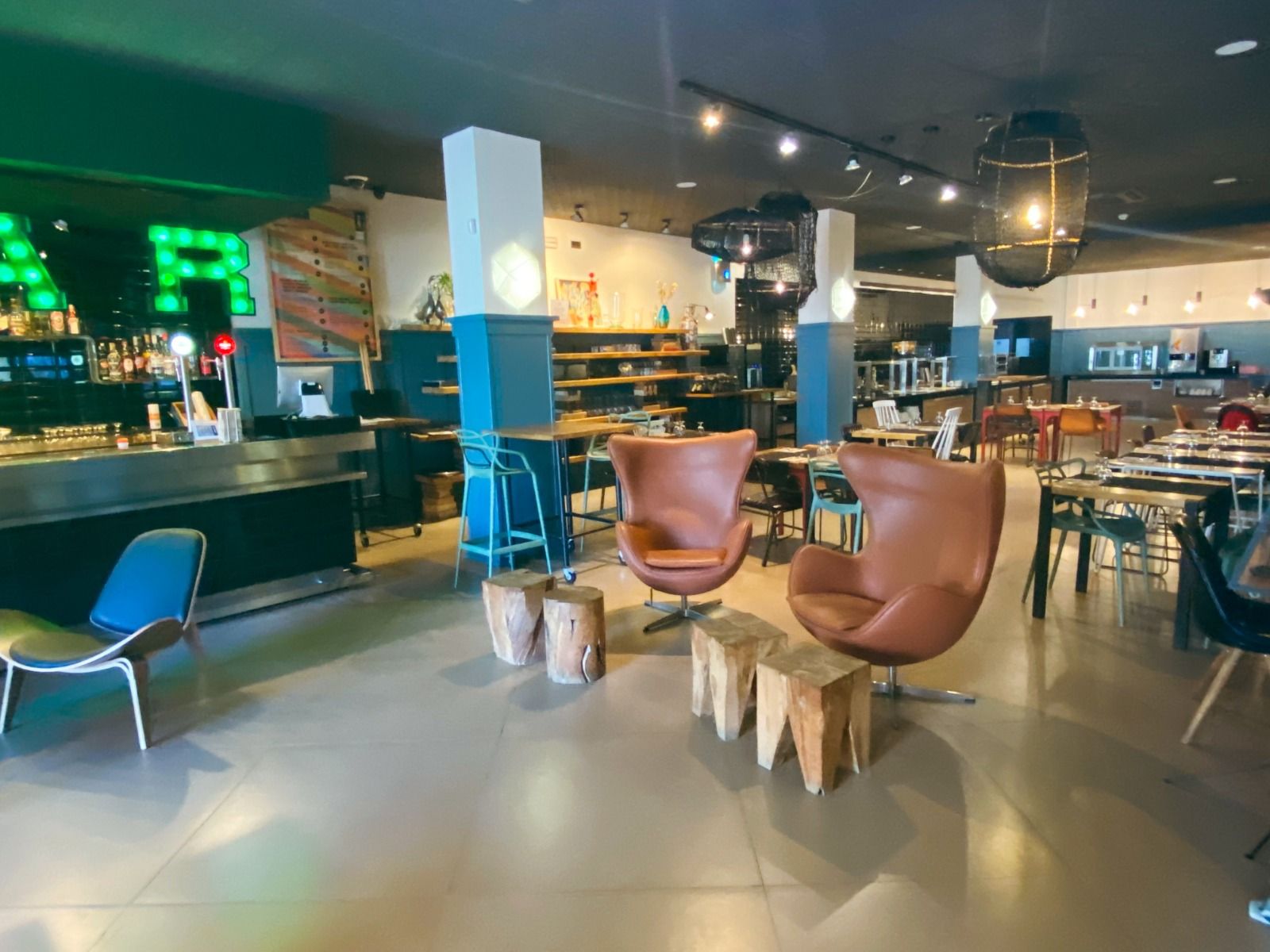 Eine gemütliche Bar und Restaurantbereich mit industriellem Design, warmem Licht und komfortablen Sitzgelegenheiten.