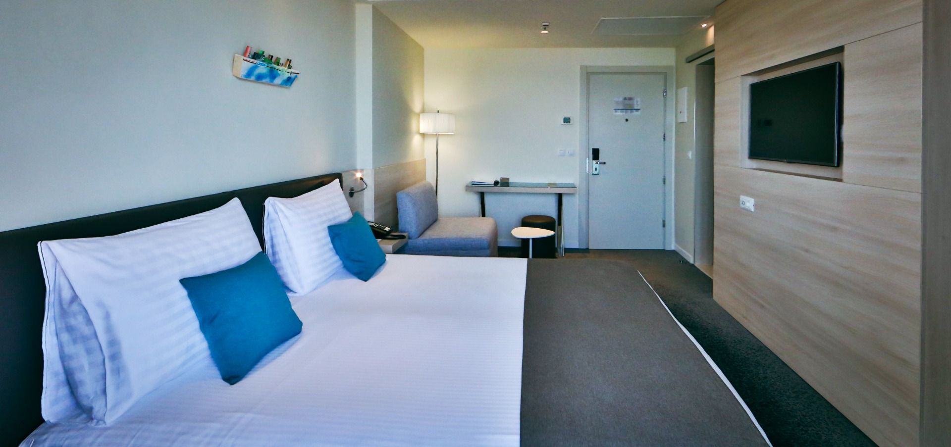 Gemütliches Doppelzimmer mit blau-weißer Bettwäsche, einer kleinen Couch, einem Tisch und einer Lampe